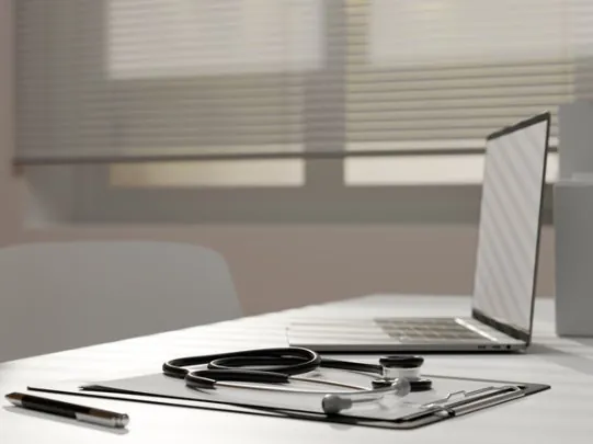 Mesa de consultório com notebook e estetoscópio